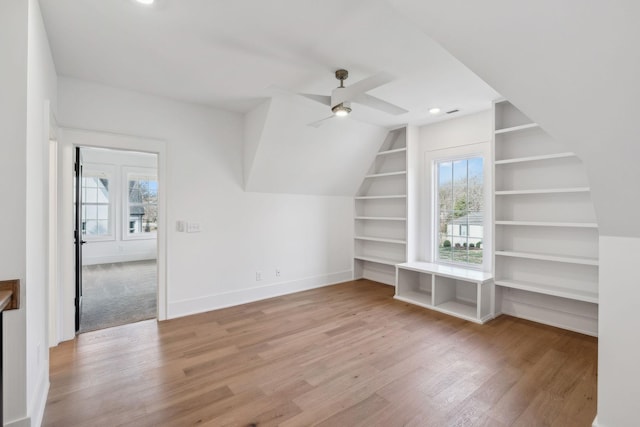 bonus room featuring lofted ceiling, built in shelves, light hardwood / wood-style floors, and ceiling fan