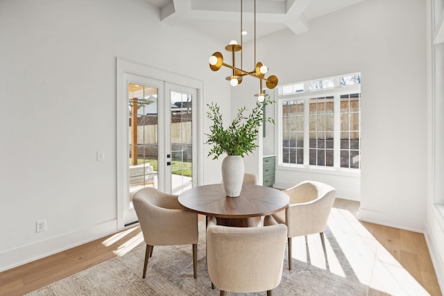 dining room with beamed ceiling, a notable chandelier, french doors, and light wood-type flooring