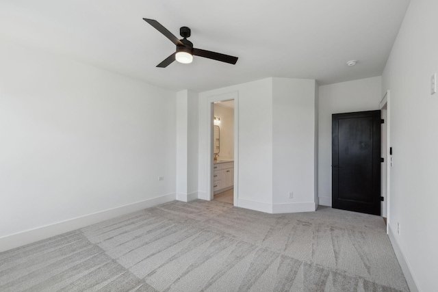 unfurnished bedroom featuring ensuite bathroom, light colored carpet, and ceiling fan