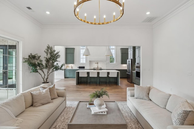 living room with an inviting chandelier, hardwood / wood-style flooring, and ornamental molding