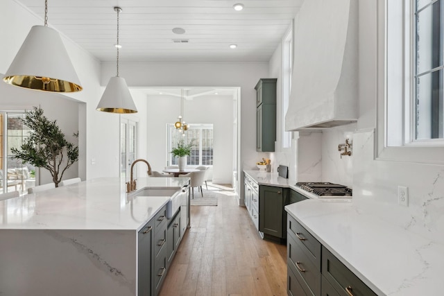 kitchen with pendant lighting, decorative backsplash, custom exhaust hood, and an island with sink