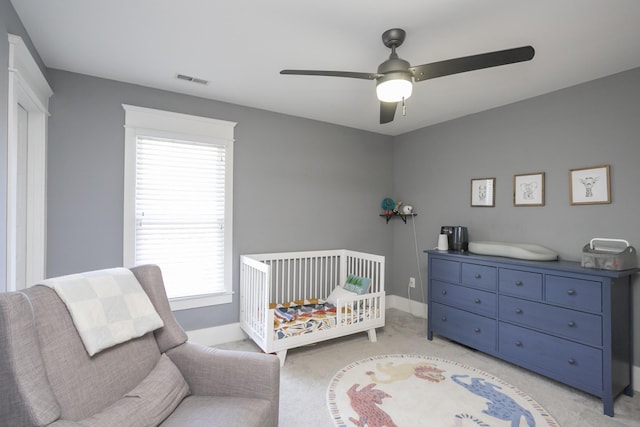 carpeted bedroom with a nursery area and ceiling fan