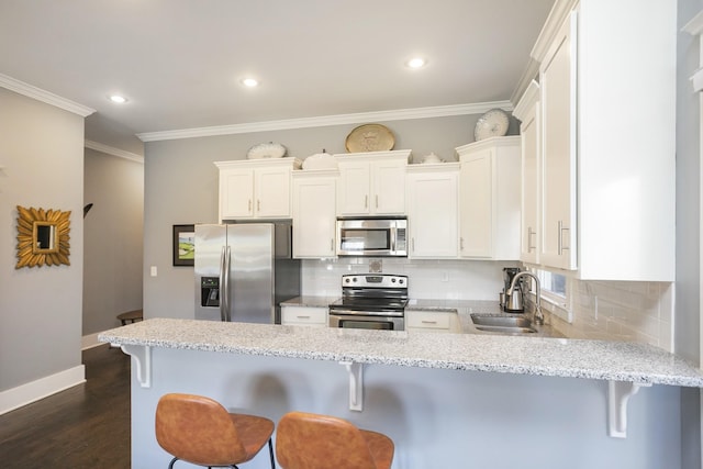 kitchen featuring sink, white cabinetry, tasteful backsplash, appliances with stainless steel finishes, and a kitchen breakfast bar