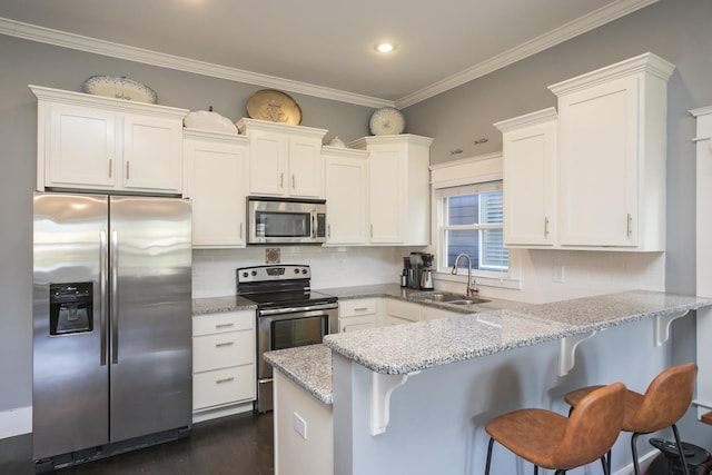 kitchen with white cabinetry, appliances with stainless steel finishes, sink, and a breakfast bar