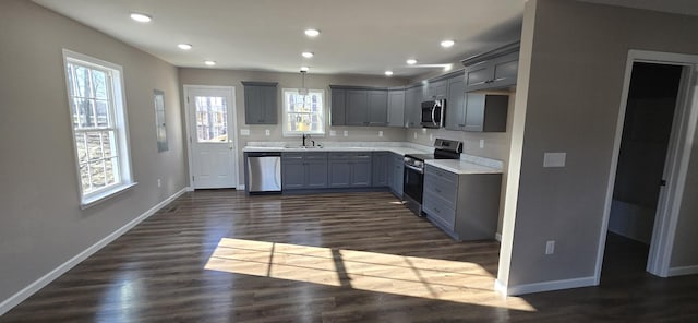 kitchen featuring sink, appliances with stainless steel finishes, gray cabinetry, hanging light fixtures, and dark hardwood / wood-style flooring