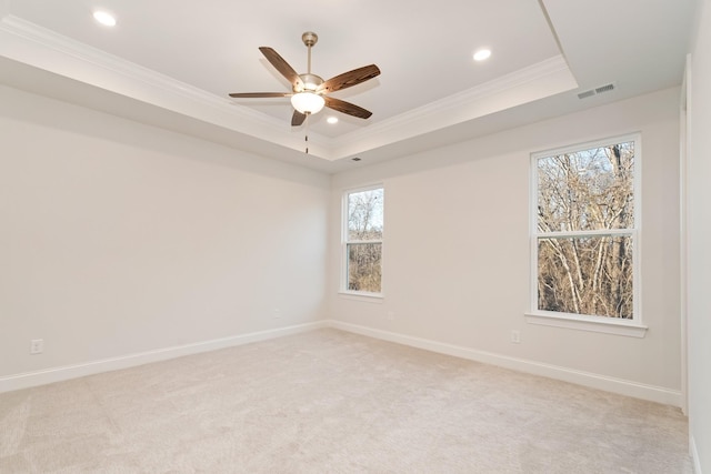 empty room with crown molding, a raised ceiling, visible vents, light carpet, and baseboards