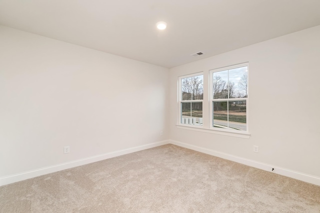 empty room featuring light colored carpet, visible vents, and baseboards