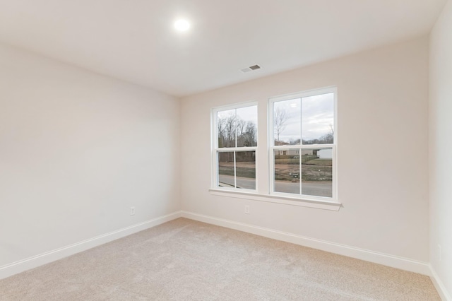 empty room featuring light carpet, visible vents, and baseboards