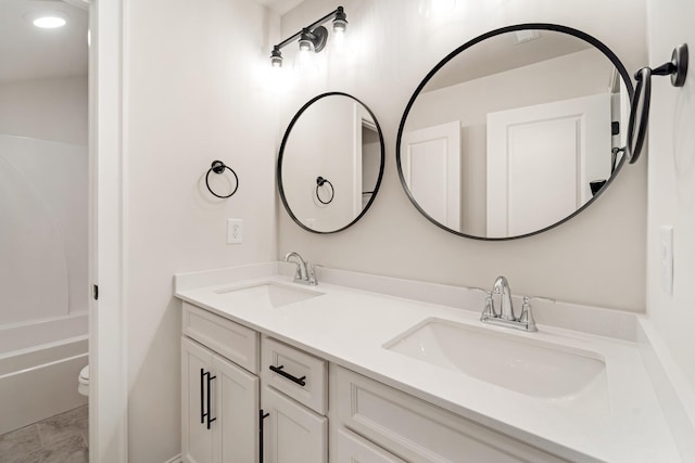 bathroom with a sink, toilet, and double vanity