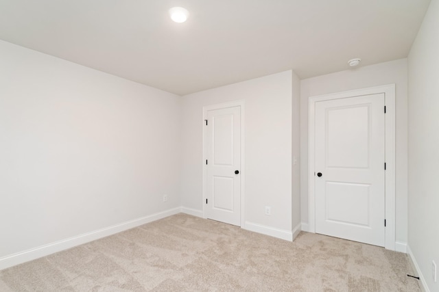 unfurnished bedroom featuring light carpet and baseboards