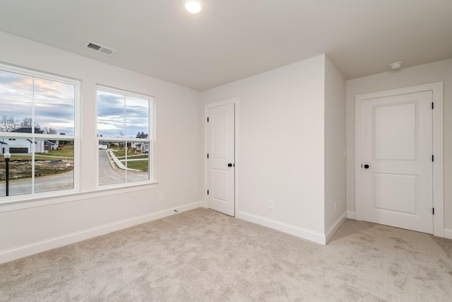 spare room featuring baseboards, visible vents, and light colored carpet