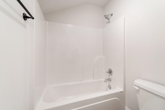 bathroom with toilet, vaulted ceiling, and tub / shower combination