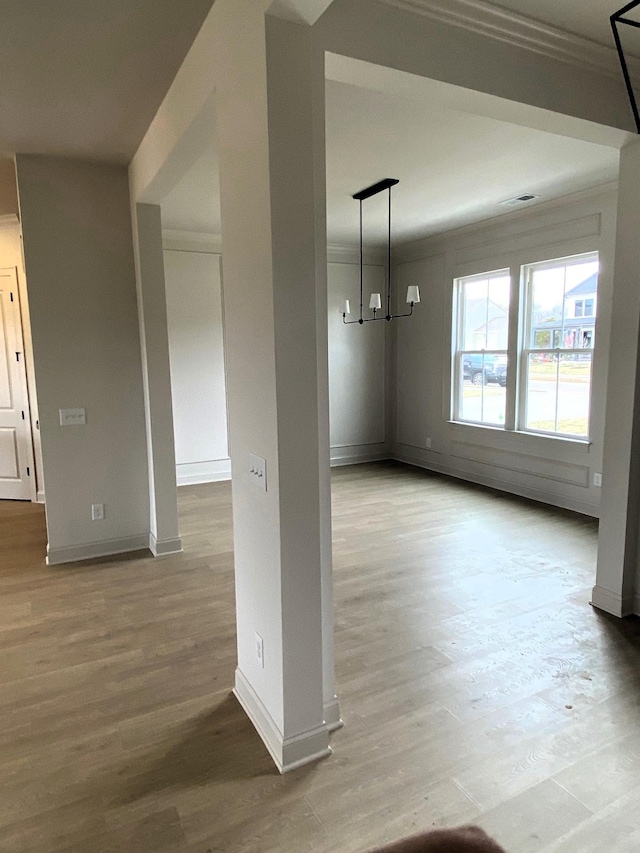 unfurnished dining area with a notable chandelier, ornamental molding, wood finished floors, and baseboards