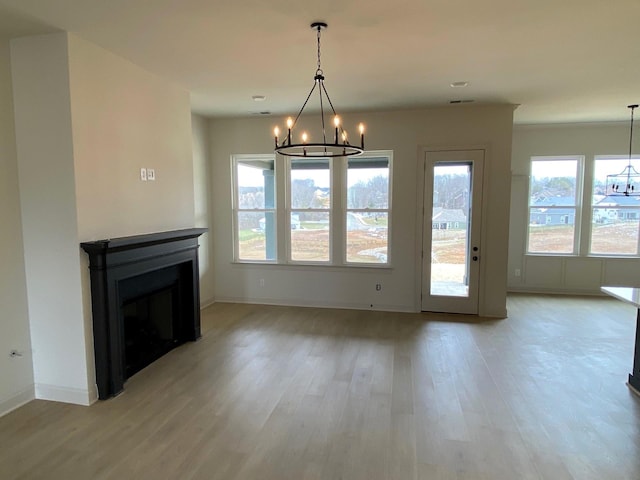 unfurnished living room featuring light wood finished floors, baseboards, a fireplace, and a chandelier