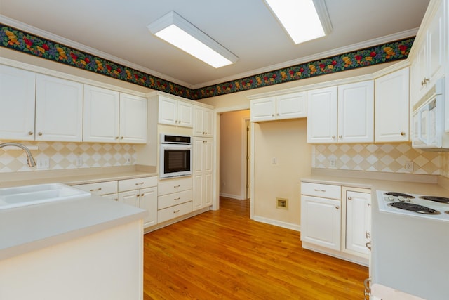 kitchen with sink, white appliances, light hardwood / wood-style flooring, white cabinetry, and ornamental molding