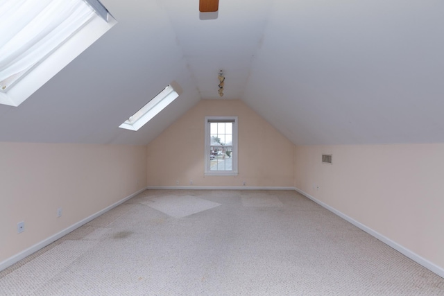 additional living space featuring vaulted ceiling and light carpet