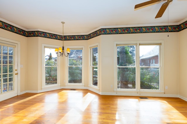 unfurnished dining area featuring crown molding, ceiling fan with notable chandelier, and light wood-type flooring