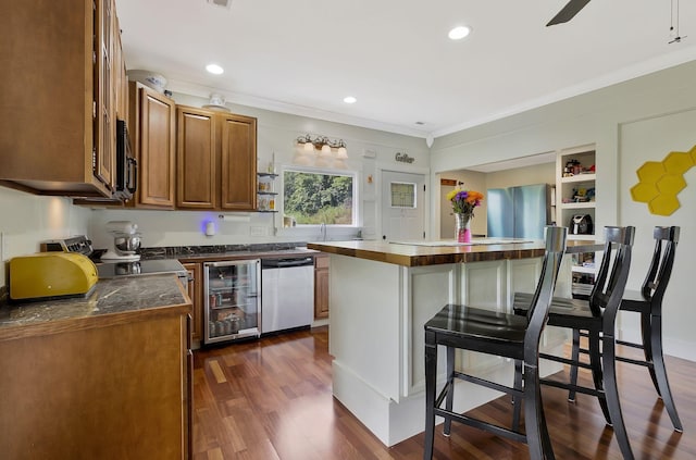 kitchen with appliances with stainless steel finishes, dark hardwood / wood-style floors, a center island, wine cooler, and ornamental molding