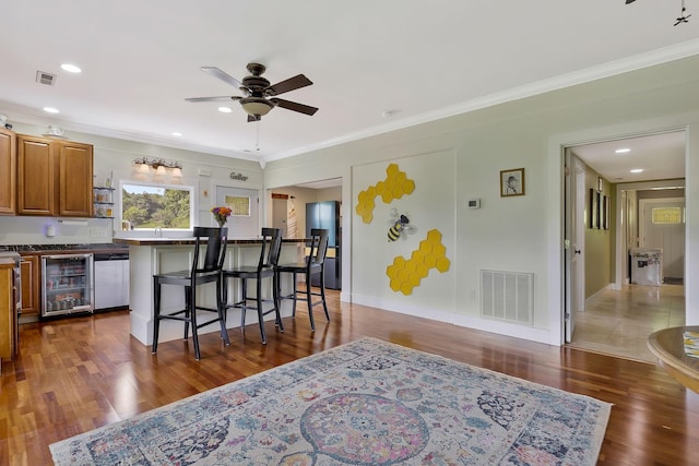 kitchen featuring a kitchen island, appliances with stainless steel finishes, wine cooler, a kitchen bar, and ceiling fan