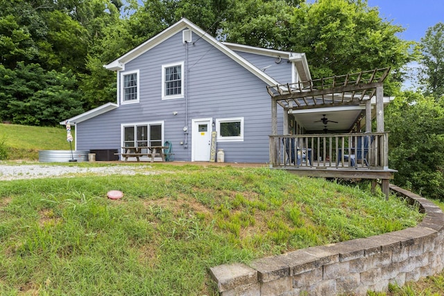 rear view of property with ceiling fan and a lawn