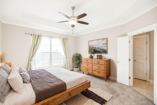 carpeted bedroom with a raised ceiling and ceiling fan