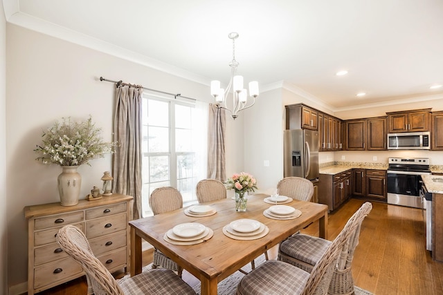 dining area with dark hardwood / wood-style flooring, crown molding, and an inviting chandelier