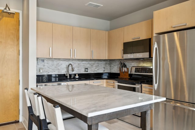 kitchen with appliances with stainless steel finishes, sink, dark stone countertops, backsplash, and light brown cabinets