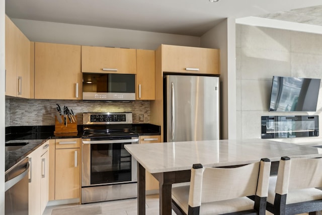 kitchen with tasteful backsplash, light brown cabinets, dark stone counters, and appliances with stainless steel finishes