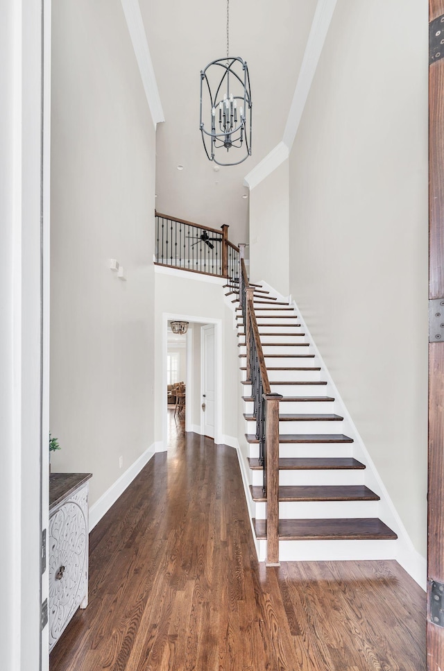 stairway with hardwood / wood-style floors, crown molding, and a chandelier