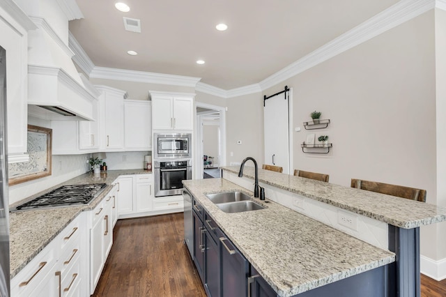 kitchen featuring a kitchen bar, sink, stainless steel appliances, a barn door, and a kitchen island with sink