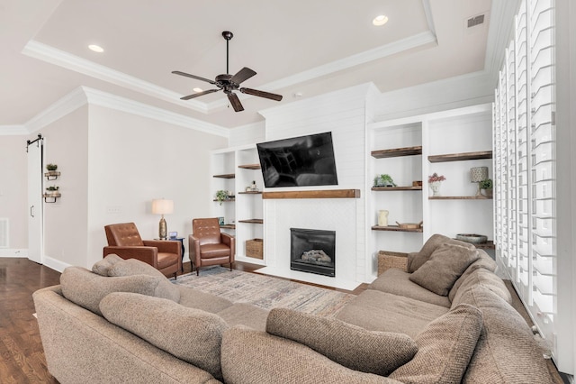 living room with ornamental molding, dark wood-type flooring, ceiling fan, and a tray ceiling