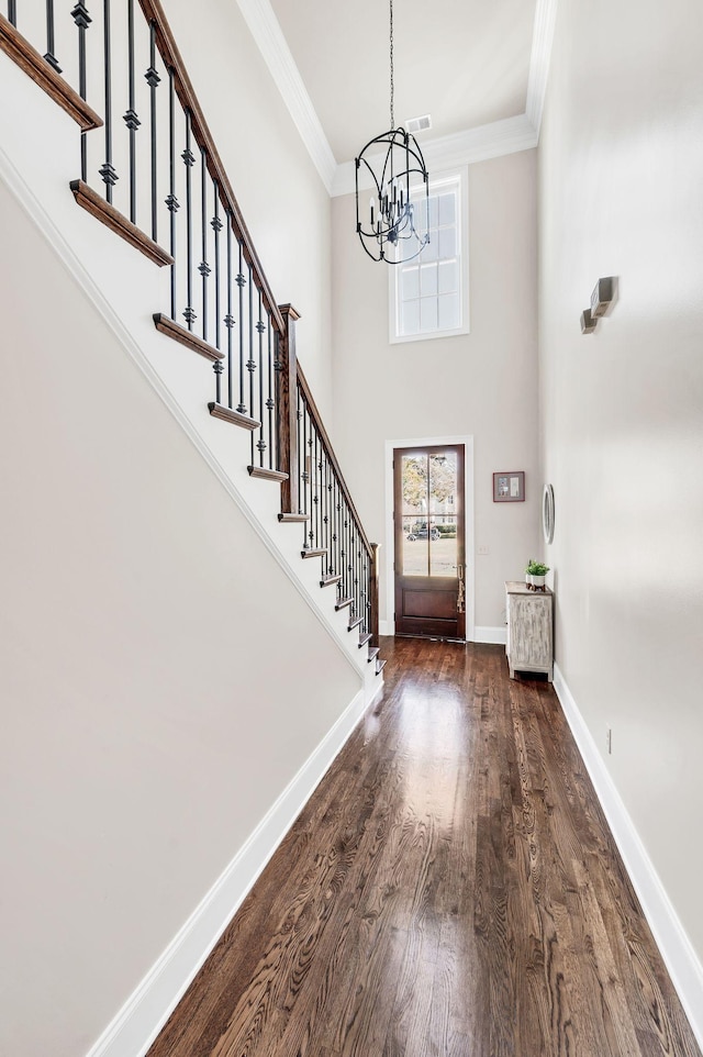 entryway featuring a notable chandelier, dark wood-type flooring, and ornamental molding