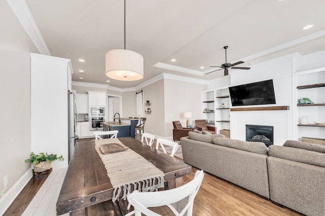 dining space featuring ceiling fan, ornamental molding, wood-type flooring, and a tray ceiling