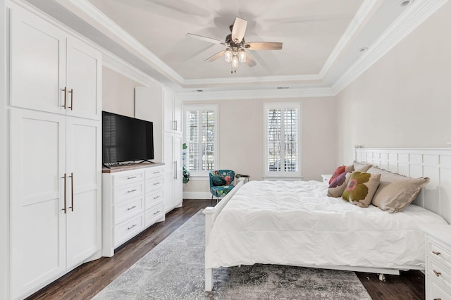 bedroom featuring dark wood-type flooring, ceiling fan, ornamental molding, and a raised ceiling