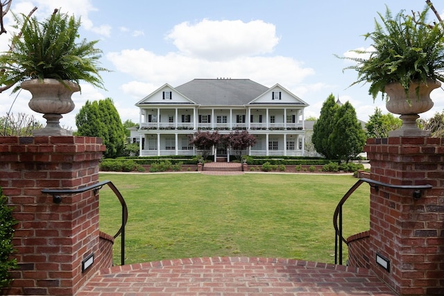 back of property with a balcony, covered porch, and a lawn