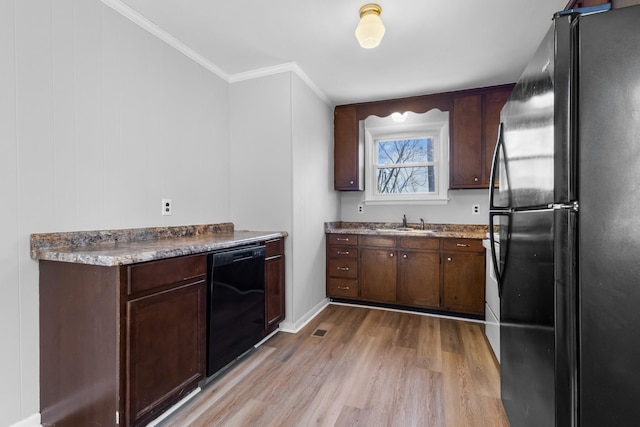 kitchen with crown molding, light hardwood / wood-style flooring, dark brown cabinets, and black appliances