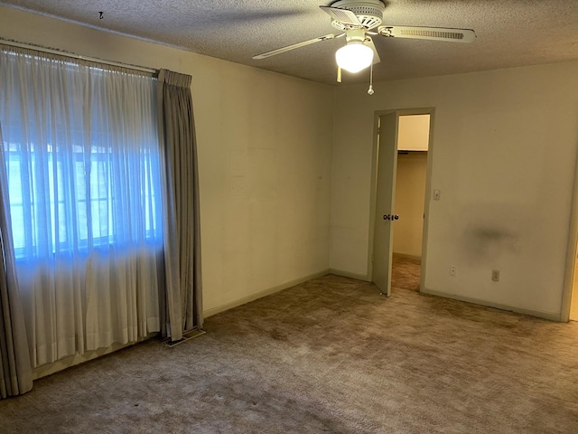 unfurnished bedroom with a walk in closet, a textured ceiling, a closet, ceiling fan, and carpet