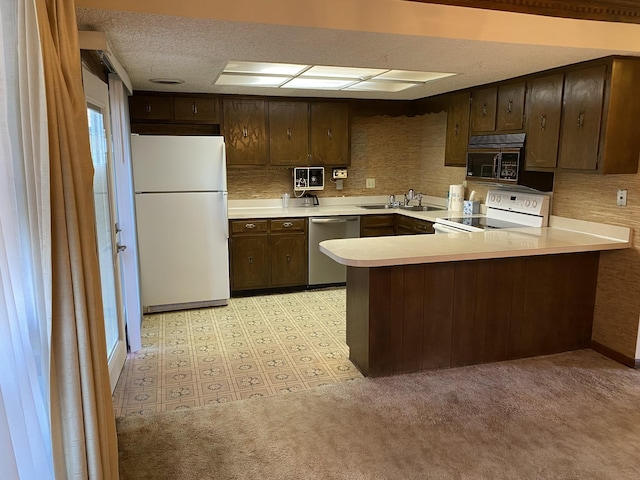 kitchen with sink, dark brown cabinets, a textured ceiling, kitchen peninsula, and white appliances