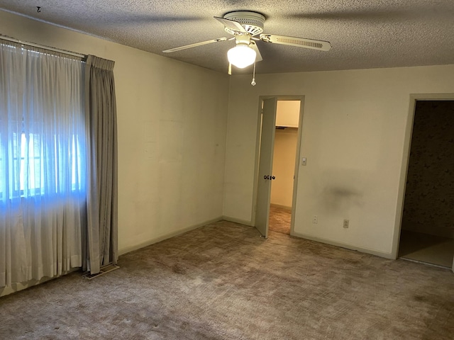 unfurnished bedroom with a spacious closet, carpet floors, a textured ceiling, and ceiling fan