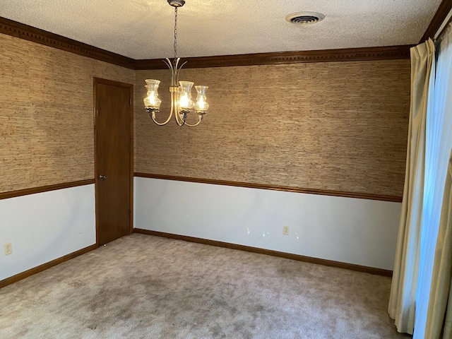 carpeted empty room with ornamental molding, a chandelier, and a textured ceiling