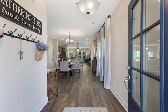 hall featuring dark wood-type flooring and an inviting chandelier