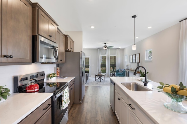 kitchen featuring dark wood-type flooring, sink, hanging light fixtures, stainless steel appliances, and decorative backsplash