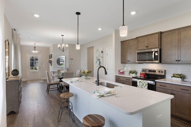 kitchen featuring a kitchen bar, sink, dark hardwood / wood-style floors, an island with sink, and stainless steel appliances