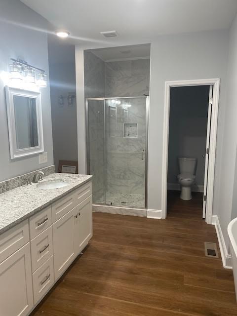 full bath featuring vanity, a shower stall, toilet, and wood finished floors