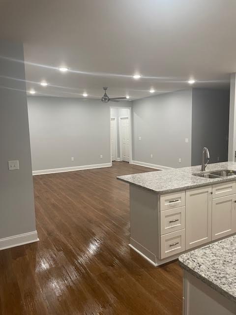 interior space featuring dark wood-type flooring, light stone countertops, sink, and white cabinets