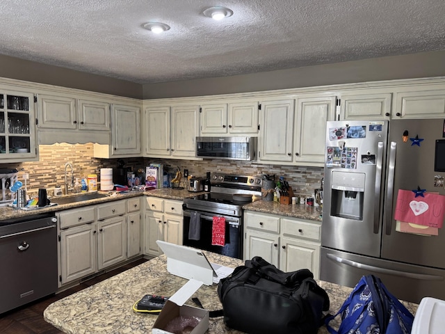 kitchen with stainless steel appliances, sink, a textured ceiling, and backsplash