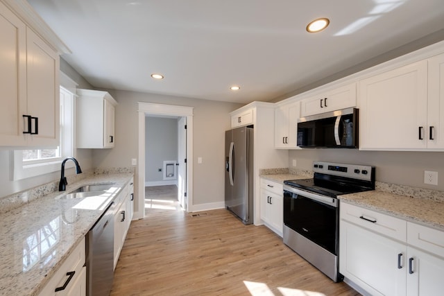 kitchen featuring white cabinetry, sink, stainless steel appliances, and light stone countertops