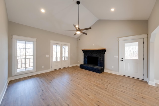 unfurnished living room with plenty of natural light, lofted ceiling, a fireplace, and light wood-type flooring