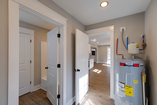 corridor with light hardwood / wood-style floors and water heater