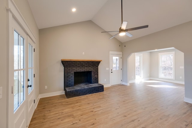 unfurnished living room featuring a brick fireplace, a healthy amount of sunlight, and light wood-type flooring